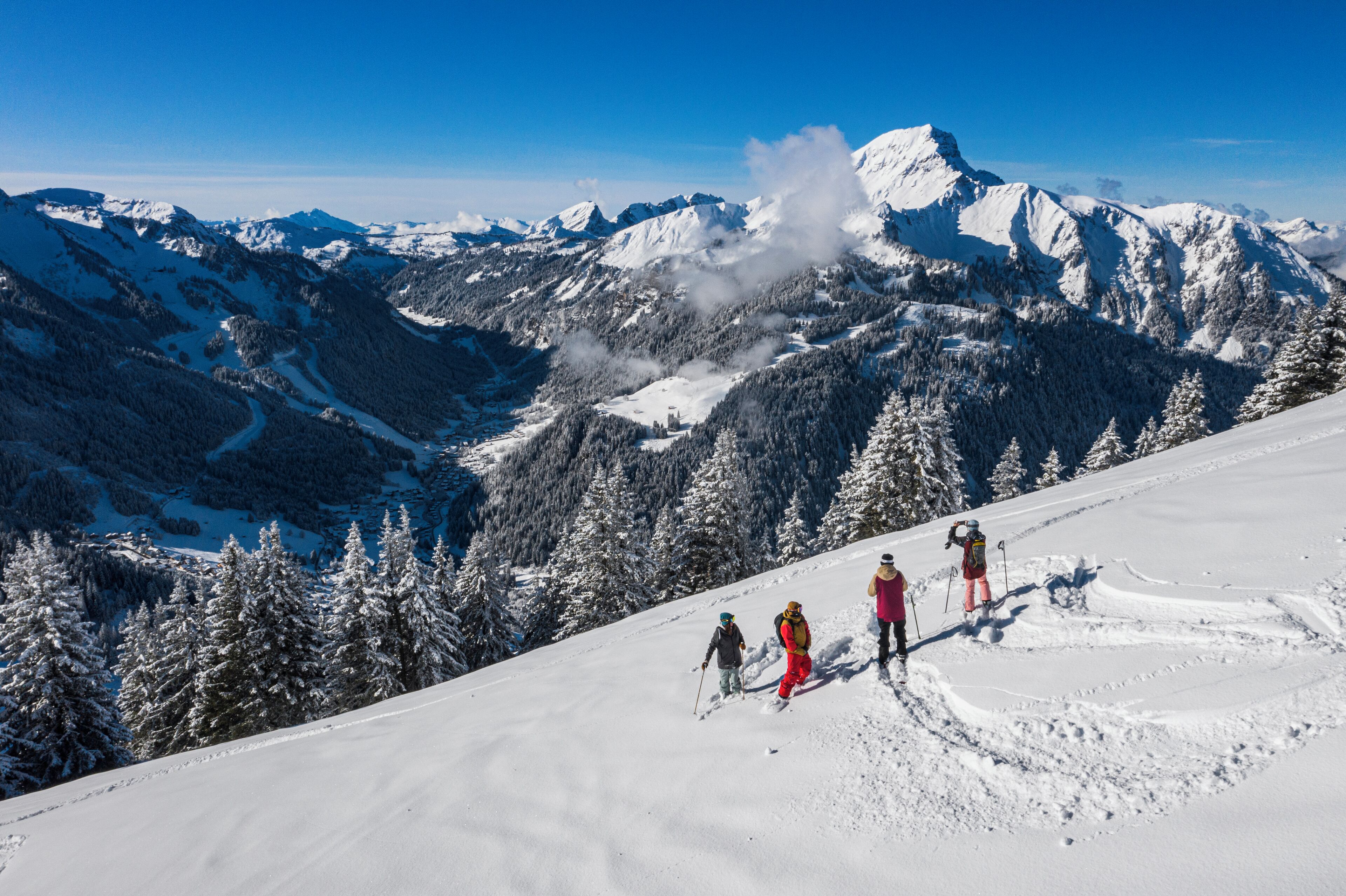A snowy mountain landscape with skiers on a slope.