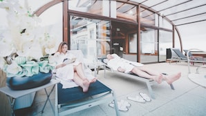A modern spa area with two reclining chairs, a large orchid arrangement, and a glass-enclosed ceiling. - Fleur De Neige Hôtel (Chatel)
