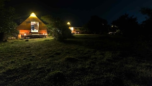 A campsite with two illuminated tents, a fire pit, and a grassy area. - Kodev (Kalpitiya)