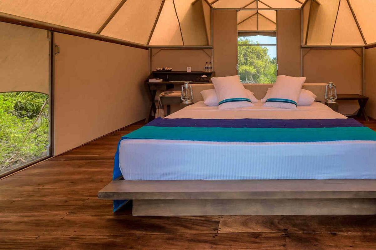 Une tente spacieuse équipée d’un lit, d’un bureau et d’une fenêtre.
