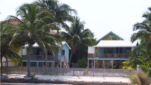 Una propiedad frente a la playa con cerco de madera, piscina y edificios de dos pisos con balcones.