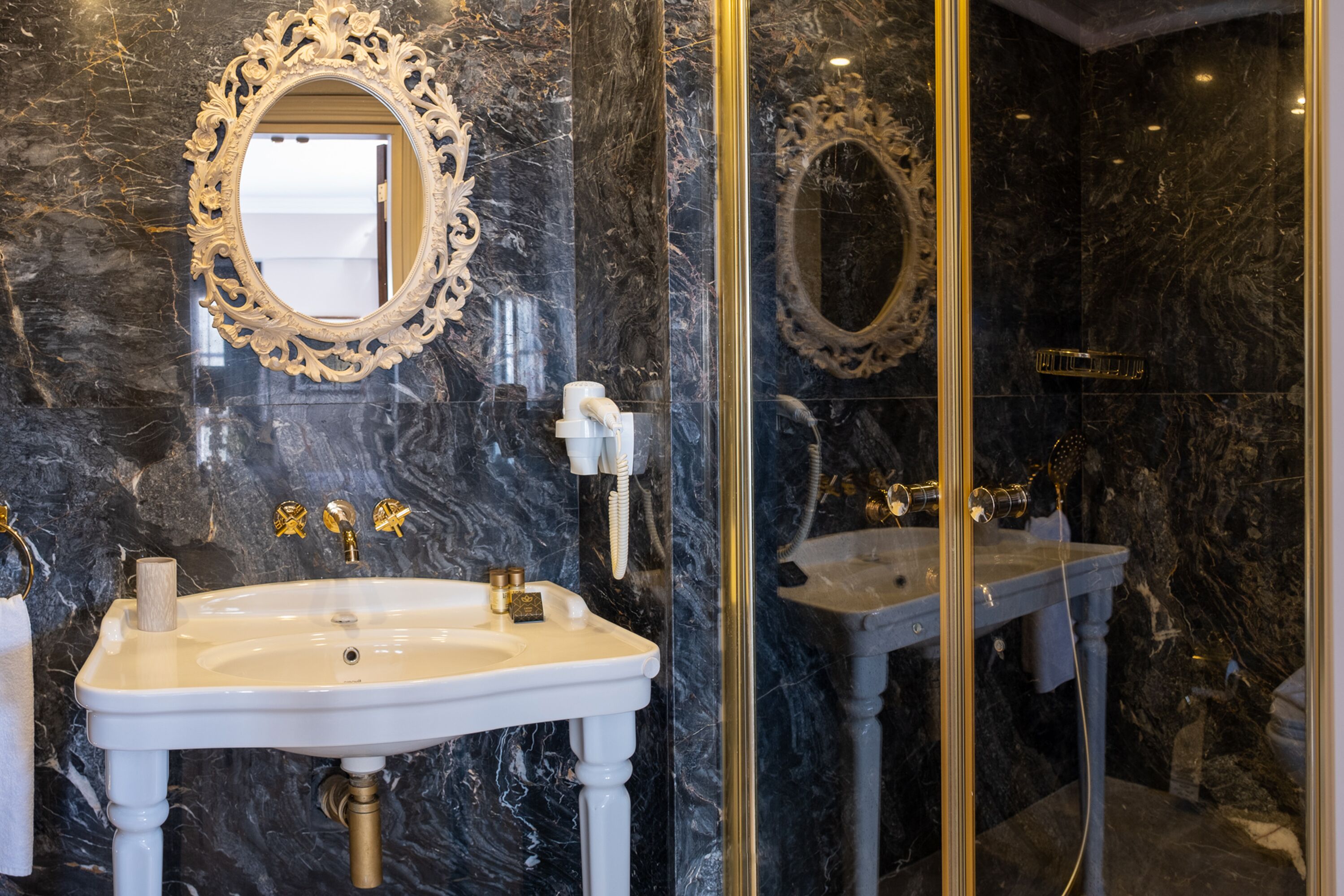 A bathroom with two sinks, marble walls, and ornate mirrors.