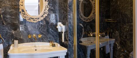 A bathroom with two sinks, marble walls, and ornate mirrors.