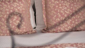 A bed with a metal headboard, two pink floral pillows, and a white pillow.