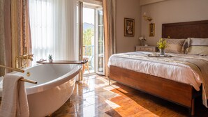 Un dormitorio con una cama grande, una bañera y un balcón con vistas.
