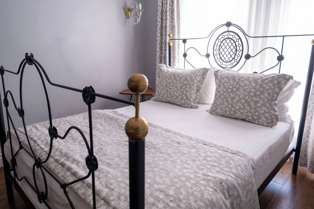 A bed with a metal frame, white bedding, and floral-patterned pillows.