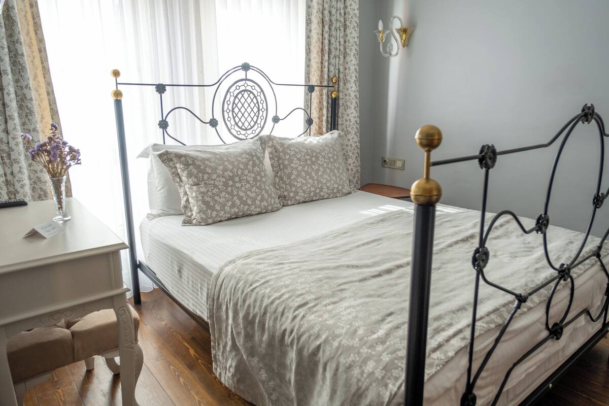 A neatly arranged bedroom with a metal bed frame, a bedside table, and a window with curtains.