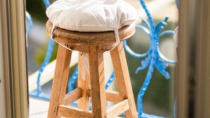 Un taburete de madera con cojín en un balcón con barandillas azules.