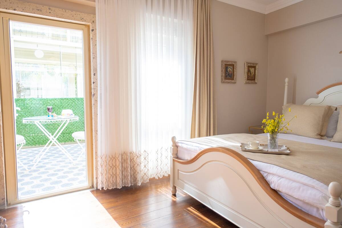 A bedroom with a bed, a small table with a tray, and a vase with flowers.