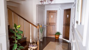 Una escalera de madera con barandilla blanca, una planta en maceta y un florero con flores.