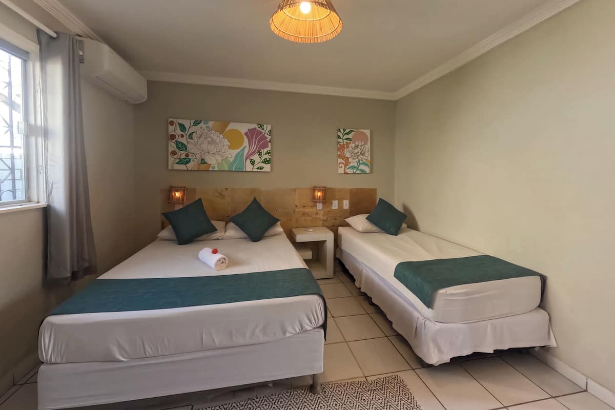 A hotel room with two beds, a patterned rug, and two wall art pieces.