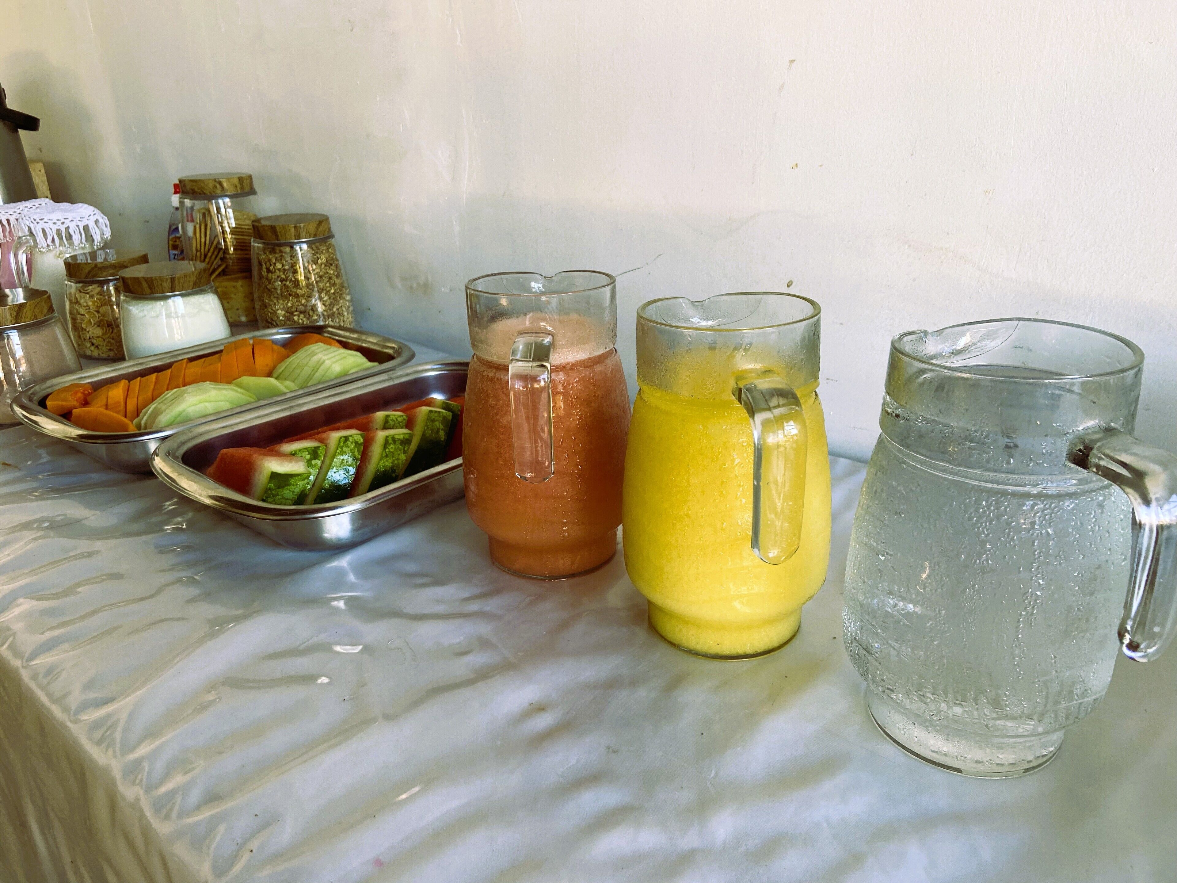 A table with various beverages and a fruit tray.