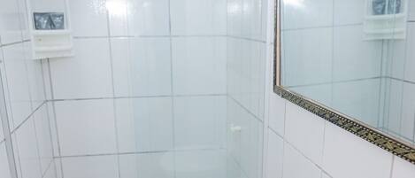 A bathroom with a glass shower enclosure, a sink, a toilet, and a mirror with a decorative frame.