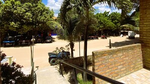 Un sendero pavimentado que conduce a un edificio con un muro de ladrillo y una palmera.