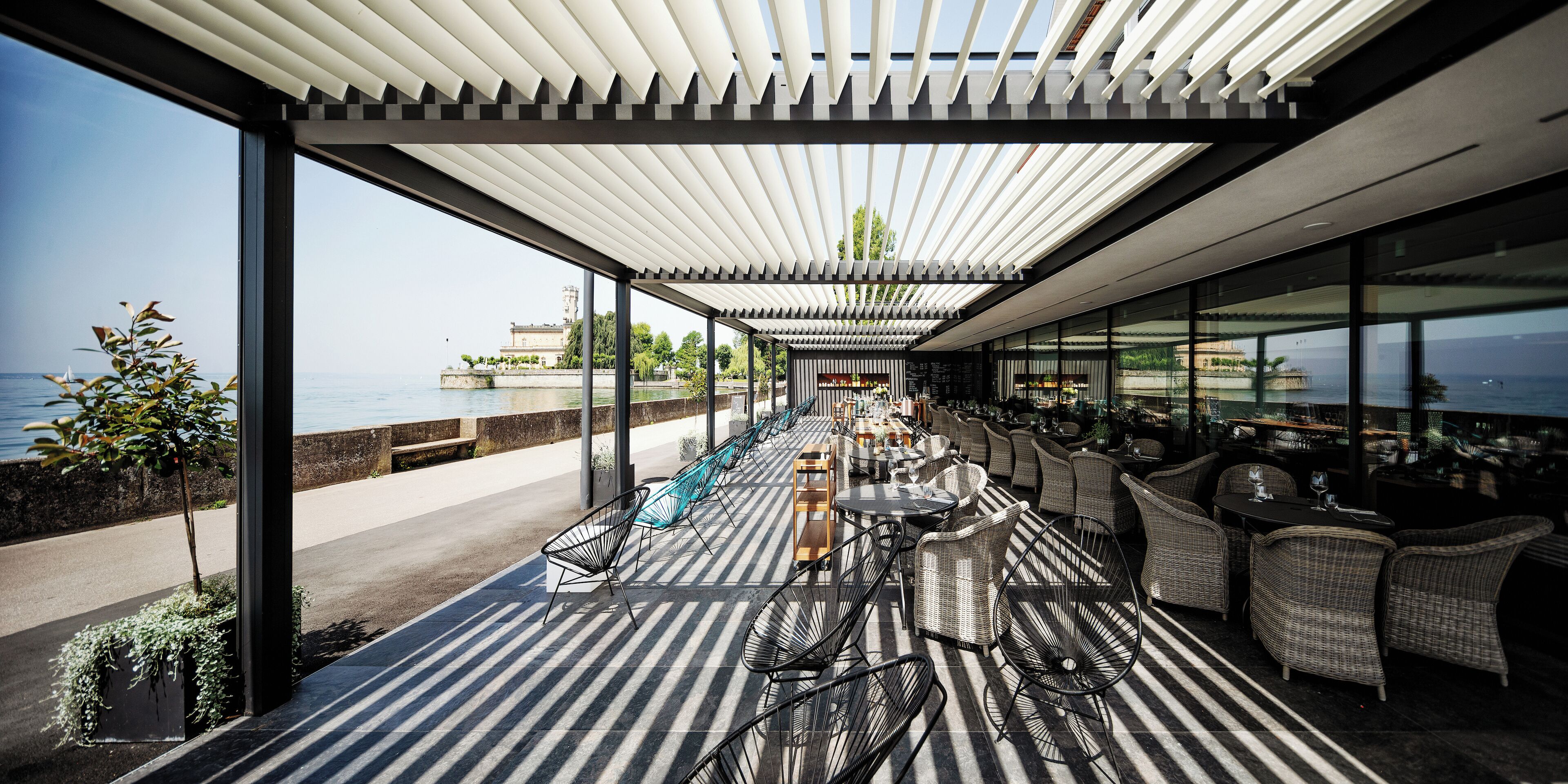 Une terrasse extérieure avec vue sur la mer, agrémentée de meubles en osier et d’une pergola.
