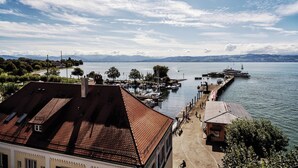 Vista al agua con un muelle, barcos y una cadena montañosa distante.