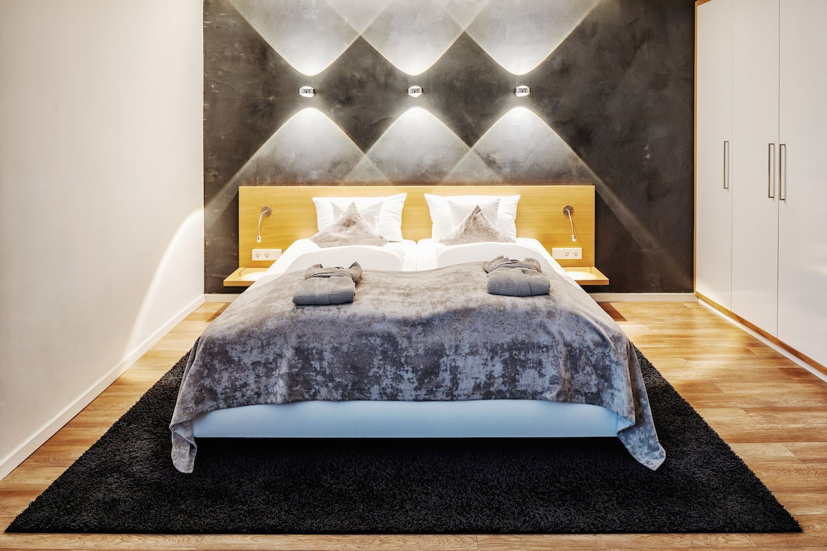 A modern bedroom with a bed, bedside tables, and a wardrobe.