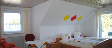 Un dormitorio con cama, escritorio, silla, radiador y ventana.