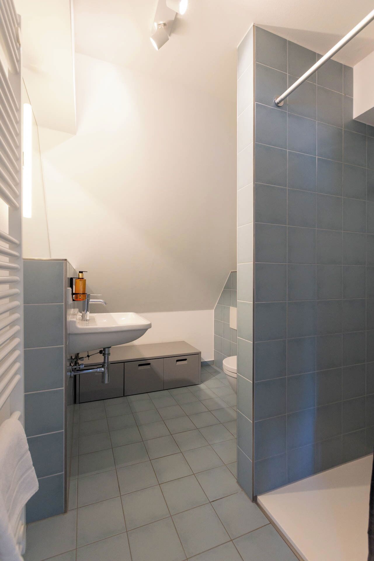 Une salle de bain moderne avec un lavabo blanc, des toilettes et un espace douche.