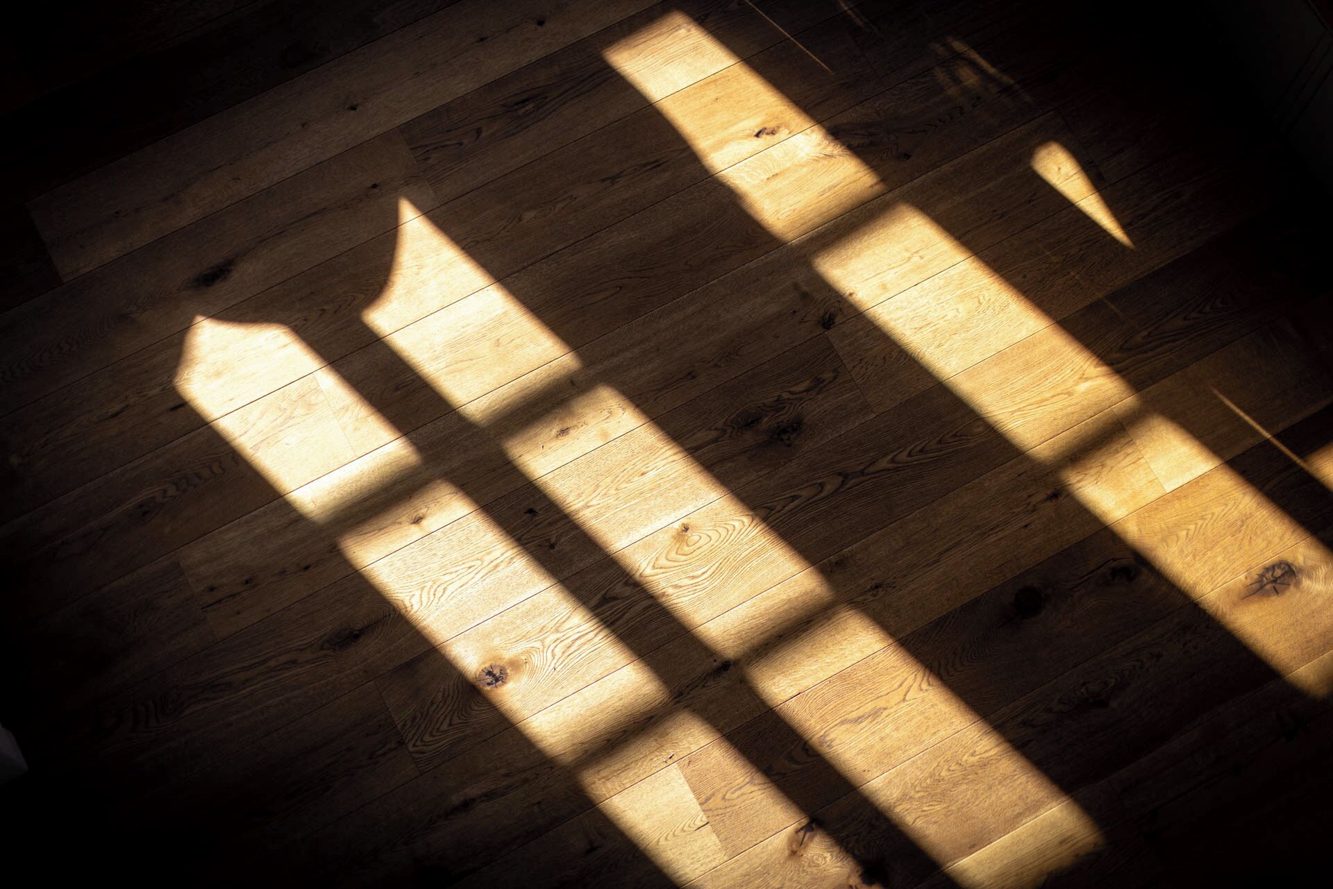 Piso de madeira com sombras projetadas por uma janela.