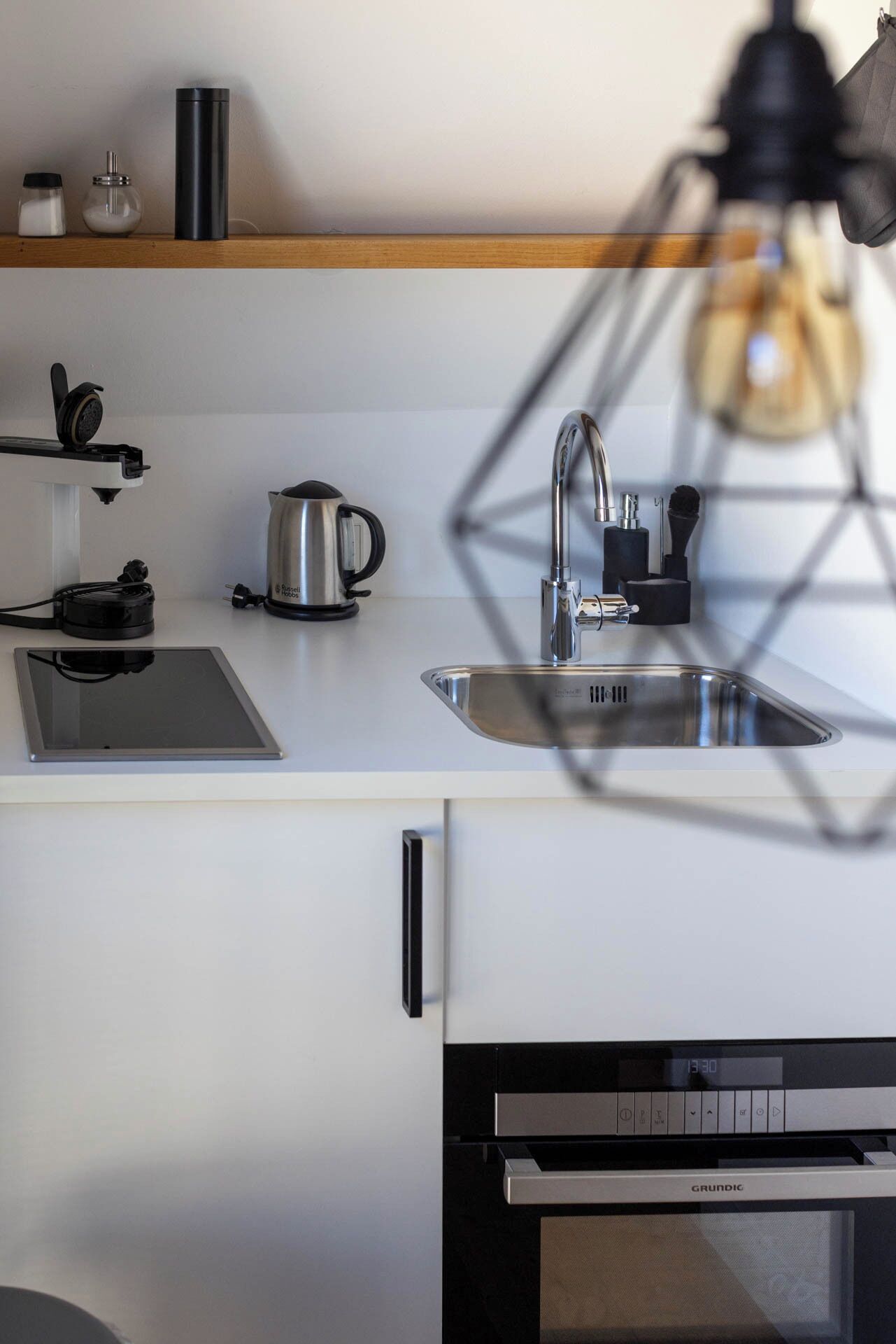 Eine moderne Küche mit einer Spüle aus Edelstahl, einem Wasserkocher und einer Kaffeemaschine auf der Arbeitsplatte.