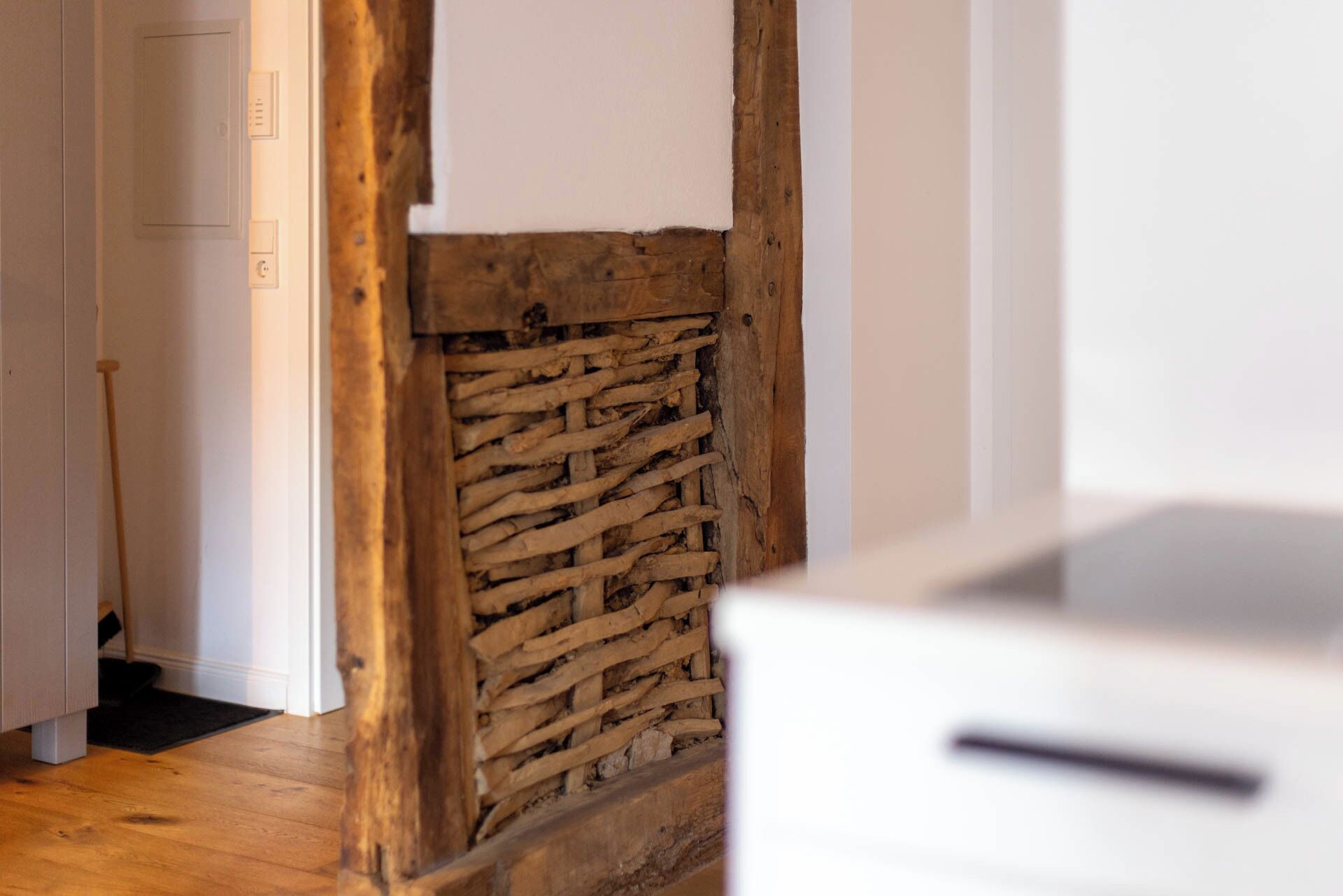 Une pièce avec un mur en pierre, des poutres en bois et une porte blanche.