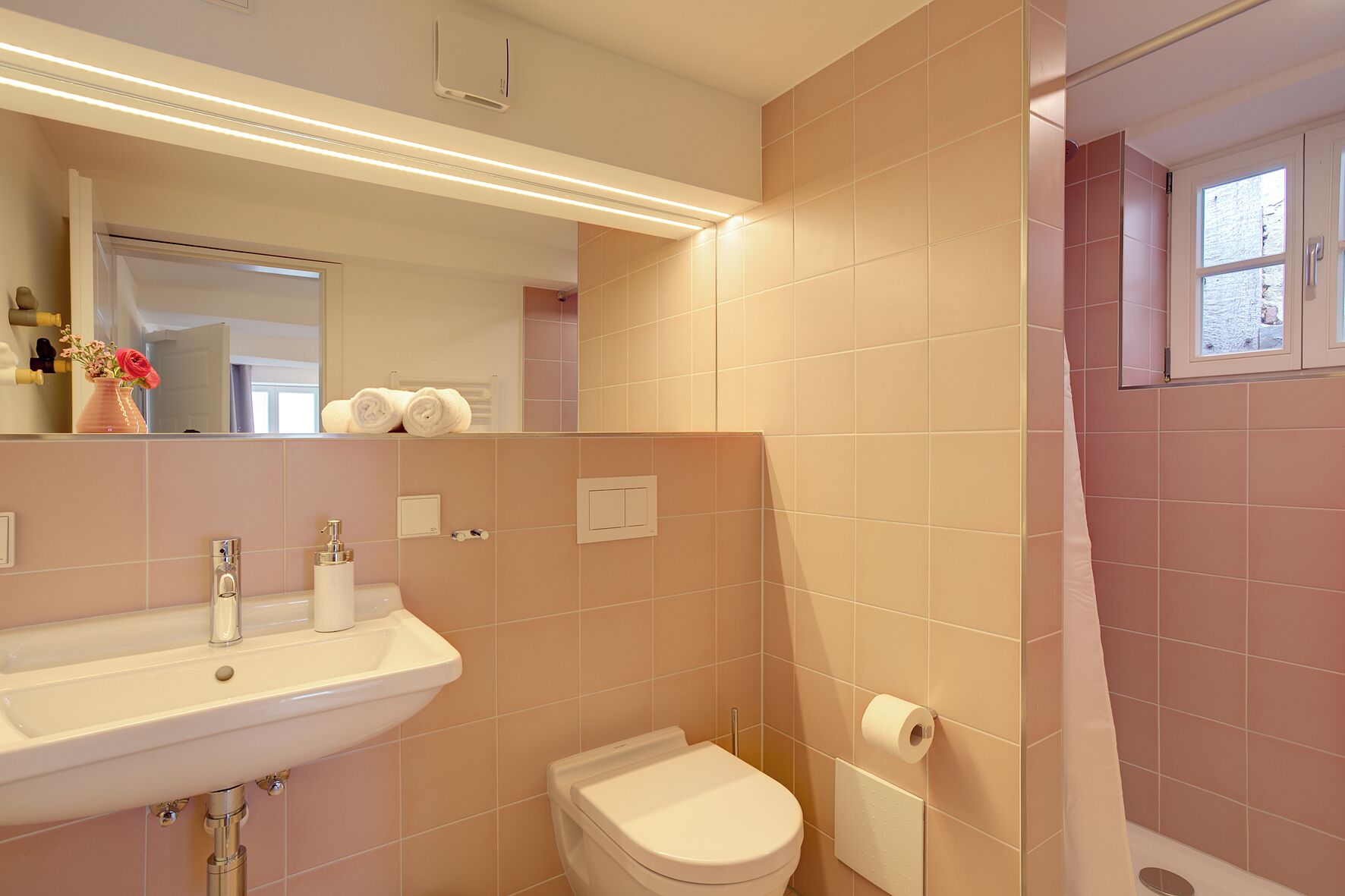 A bathroom with a sink, toilet, and shower area.