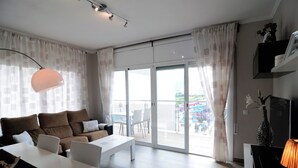 A modern living room with a sofa, coffee table, and a dining area. - HomeHolidaysRentals  Maritim V (Pineda de Mar)