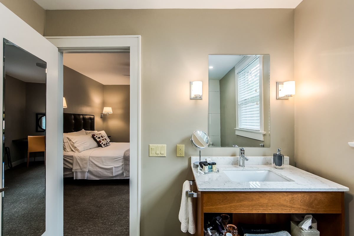 A modern hotel bathroom with a large sink, mirror, and two wall-mounted lights.