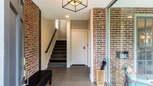 A hallway with a staircase, a bench, and a door. - Bexley Bed and Breakfast (Columbus)