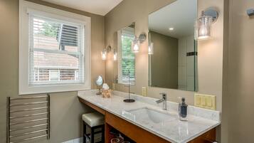 A modern bathroom with a large mirror, a white sink, and a towel rack.