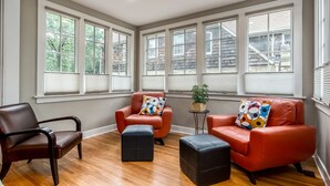 A room with three leather chairs, a black ottoman, and a small table with a plant. - Bexley Bed and Breakfast (Columbus)