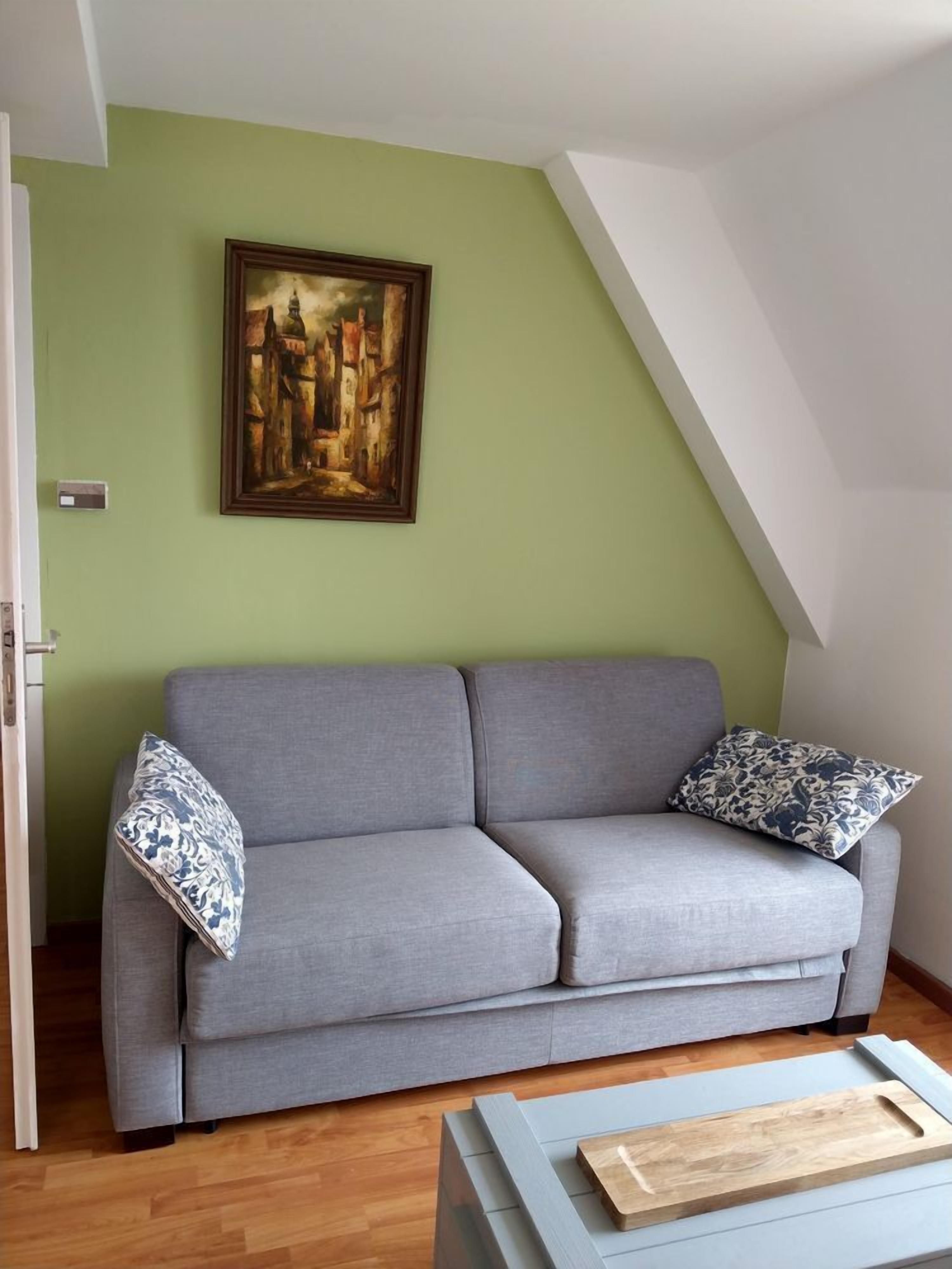 A modern living room with a grey sofa, a wooden coffee table, and a painting on the wall.