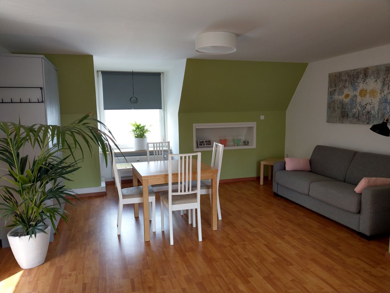 Un comedor con una mesa y sillas de madera, un sofá y una planta en maceta.