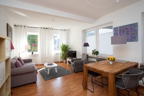 A modern living room with a sofa, a dining table, and a TV. - Wertschätzter III - Paulinenstr. (Detmold)