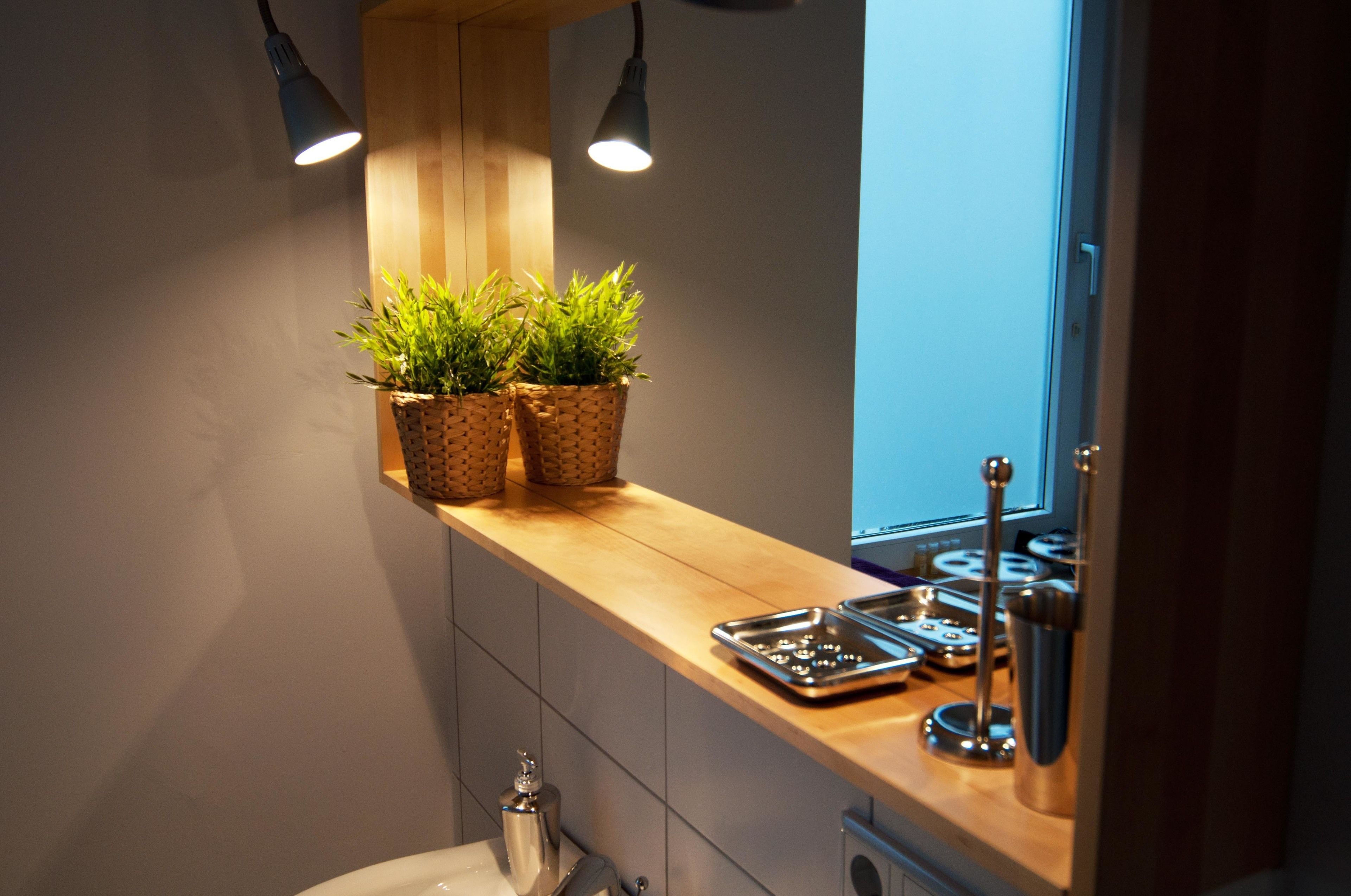 A kitchen with wooden countertops, two potted plants, a stainless steel sink, and a window with a view.