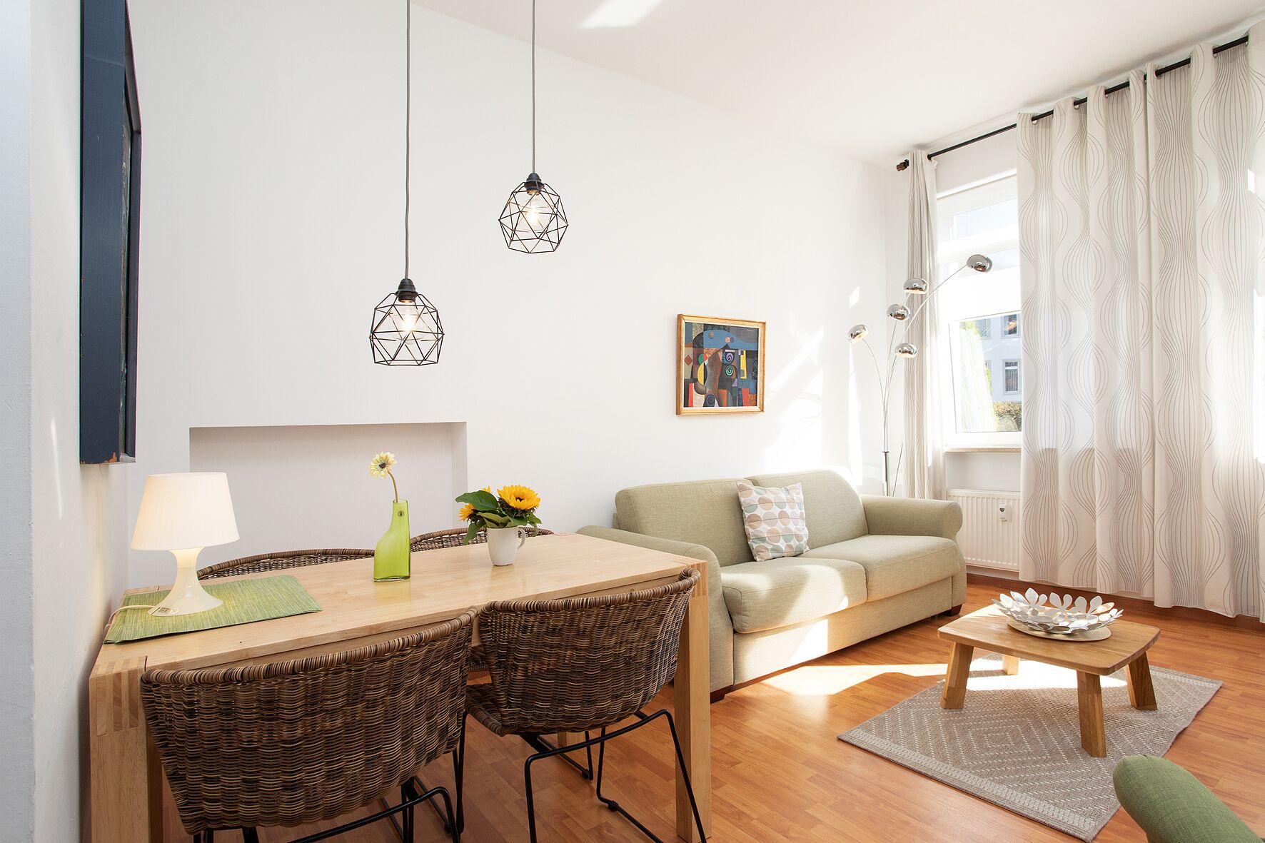 A modern living room with a dining area, a sofa, and a window with curtains.