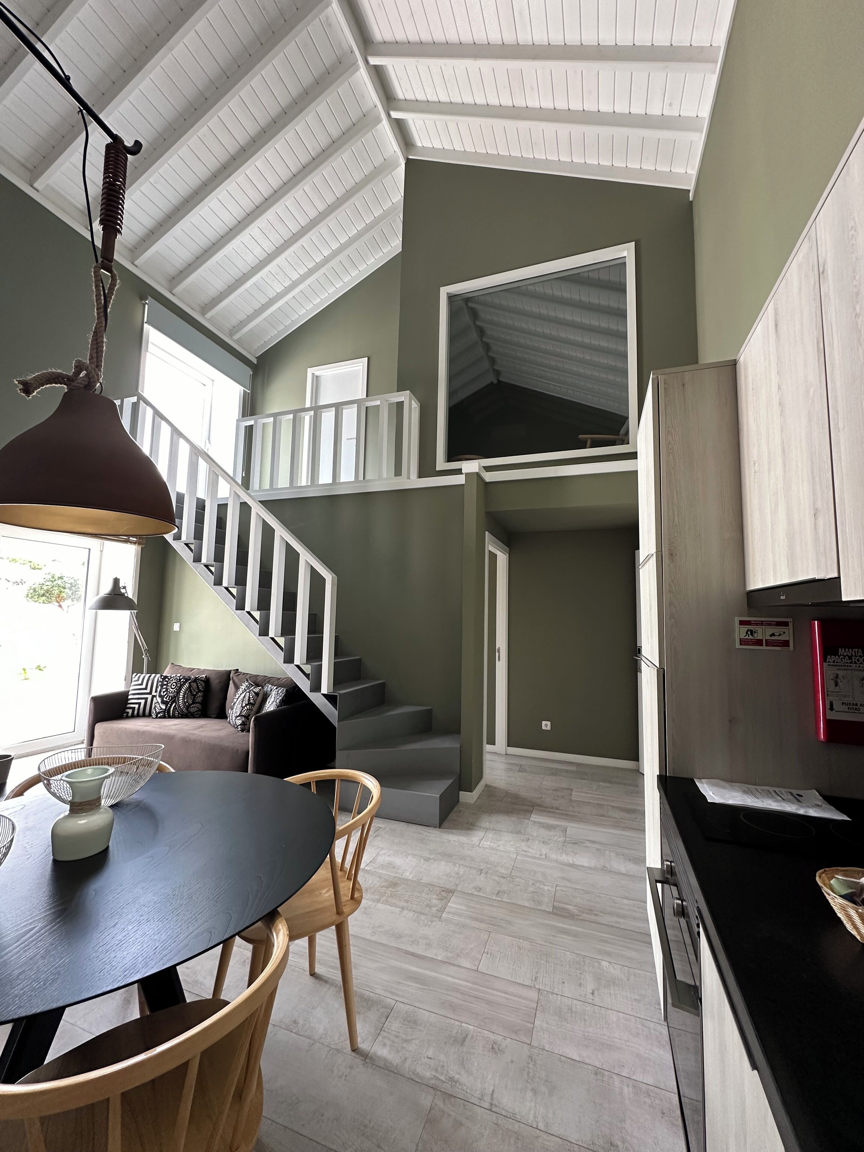 Una cocina moderna con comedor, una escalera y vistas al exterior.