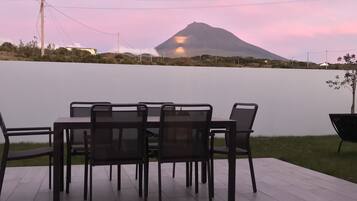 Un patio con mesa y sillas que da a un cuerpo de agua y una montaña.