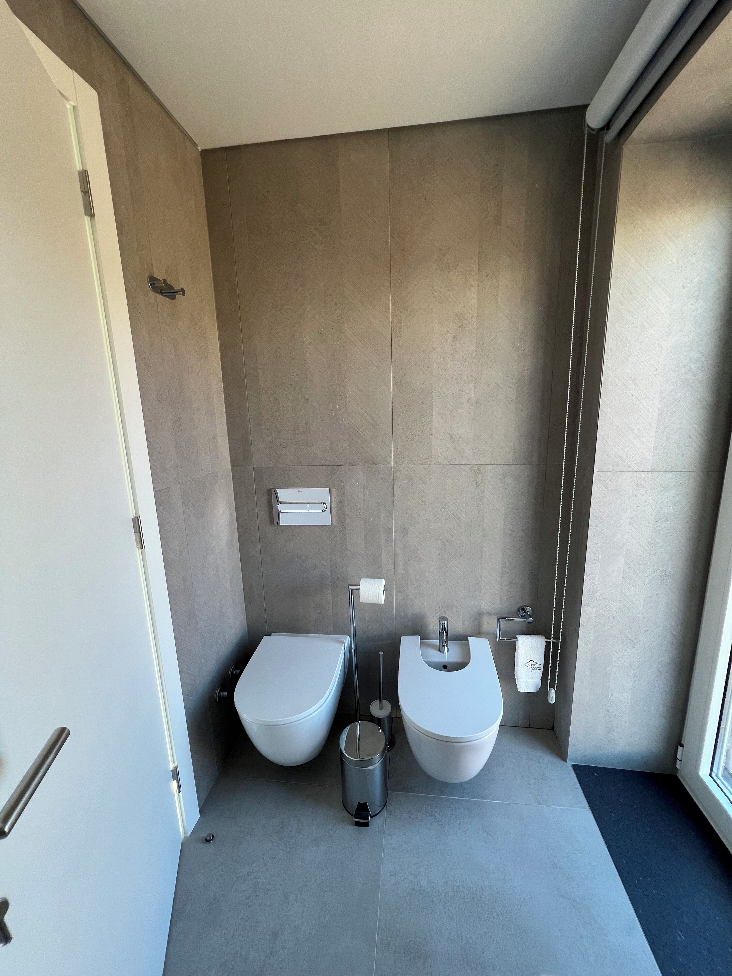 Ein modernes Badezimmer mit zwei Waschbecken, einer Toilette und einem Mülleimer.