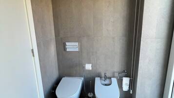 Ein modernes Badezimmer mit zwei Waschbecken, einer Toilette und einem Mülleimer.
