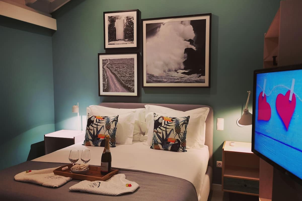 A hotel room with a bed, a TV, and three framed pictures on the wall.