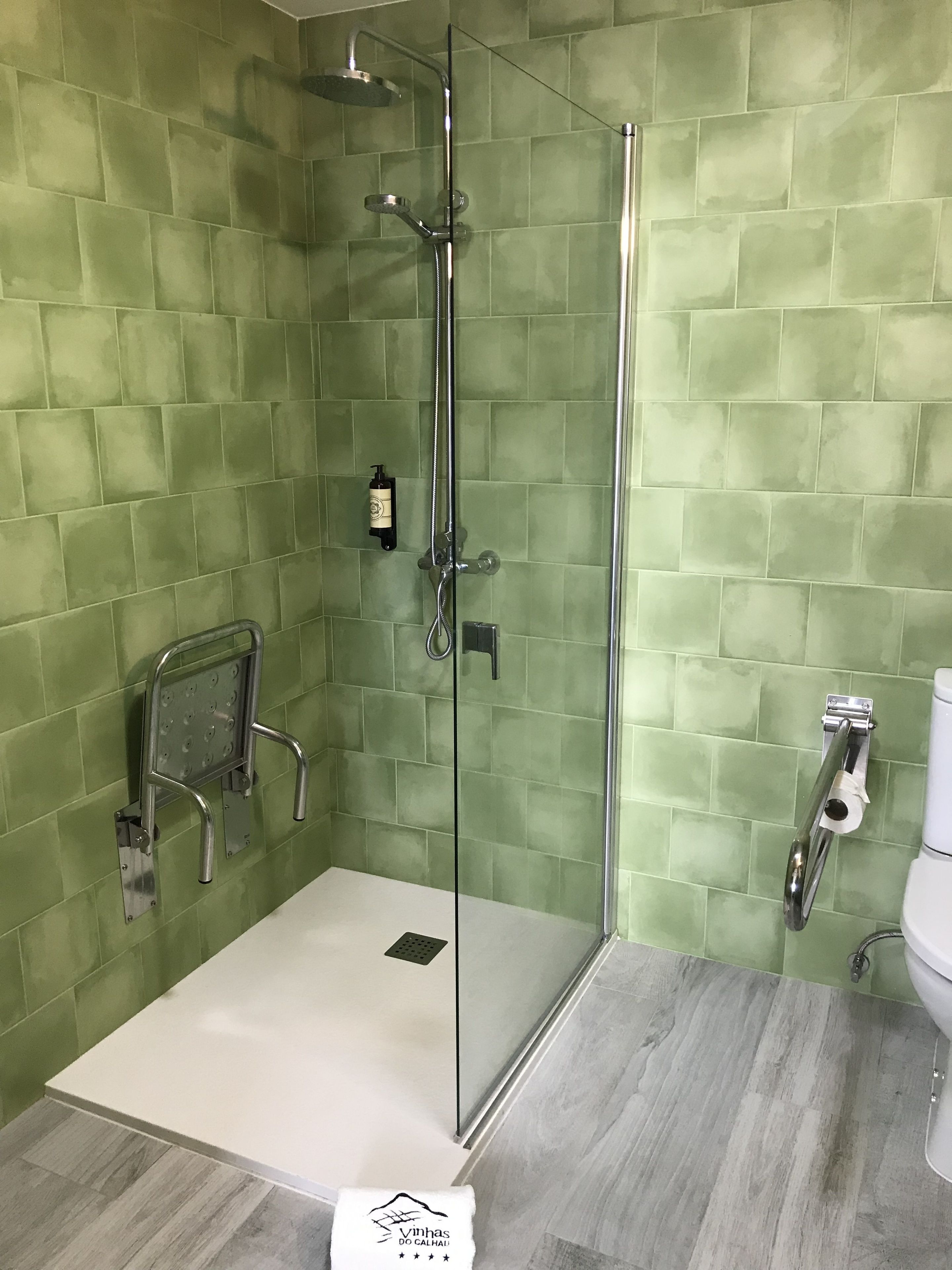 A shower with a glass door, a handheld showerhead, and a handheld shower attachment.