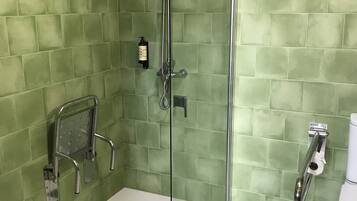 A shower with a glass door, a handheld showerhead, and a handheld shower attachment.