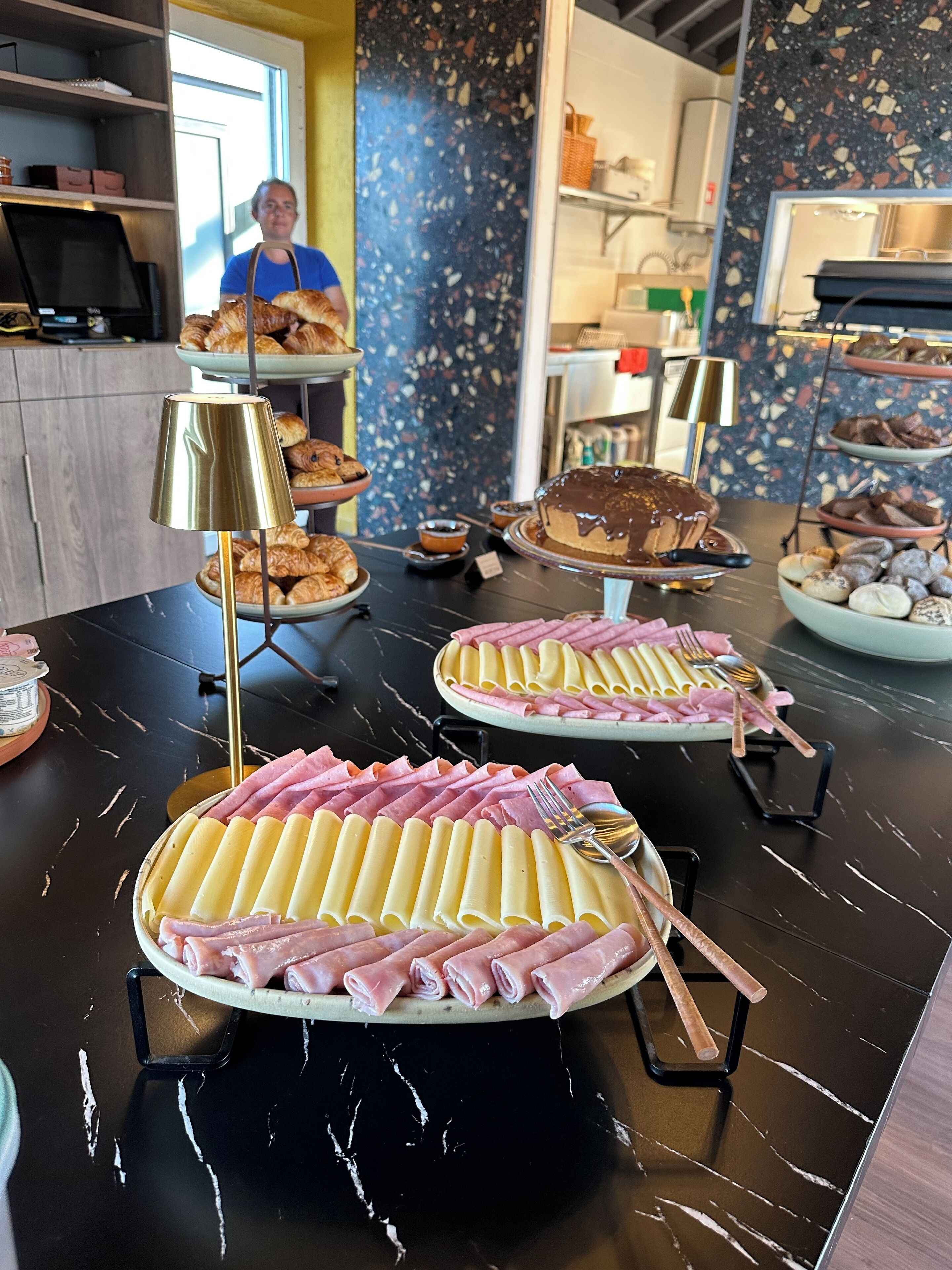 A buffet table with various food items including pasta, ham, and pastries.