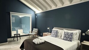 Un dormitorio moderno con una cama grande, una ventana, una silla y una mesita de noche.