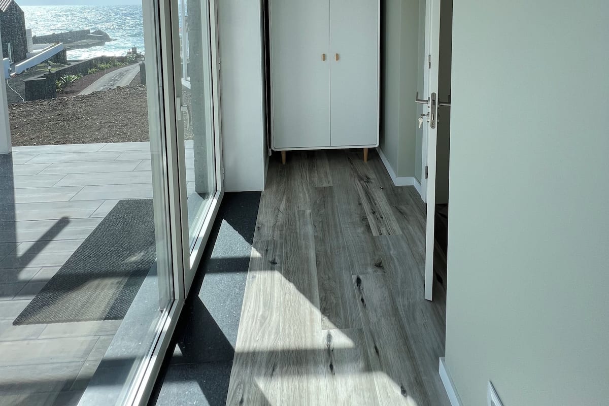 A hallway with a view of the ocean, a white wardrobe, and a door.