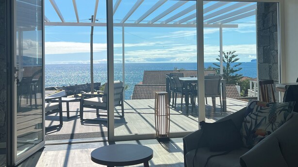 Un balcón amplio con vistas despejadas al océano y una zona de patio con mobiliario exterior.
