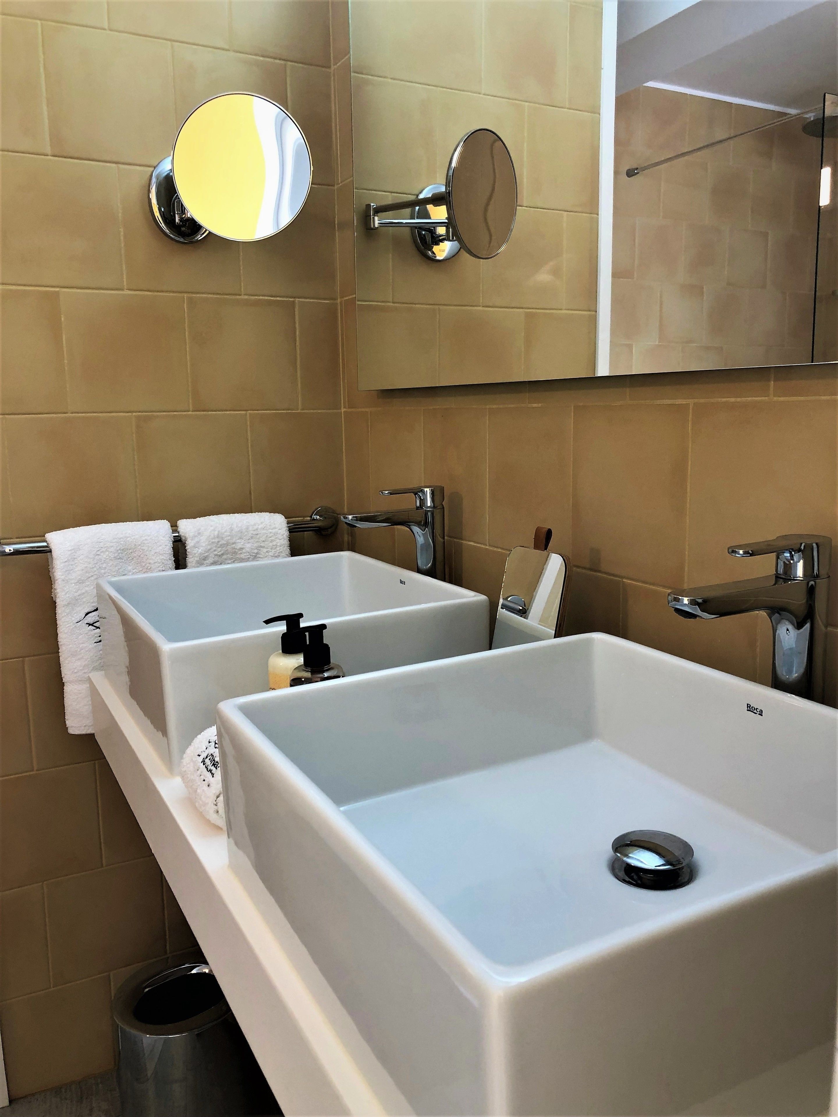 Un baño moderno con dos lavamanos rectangulares, un espejo y un perchero para toallas.