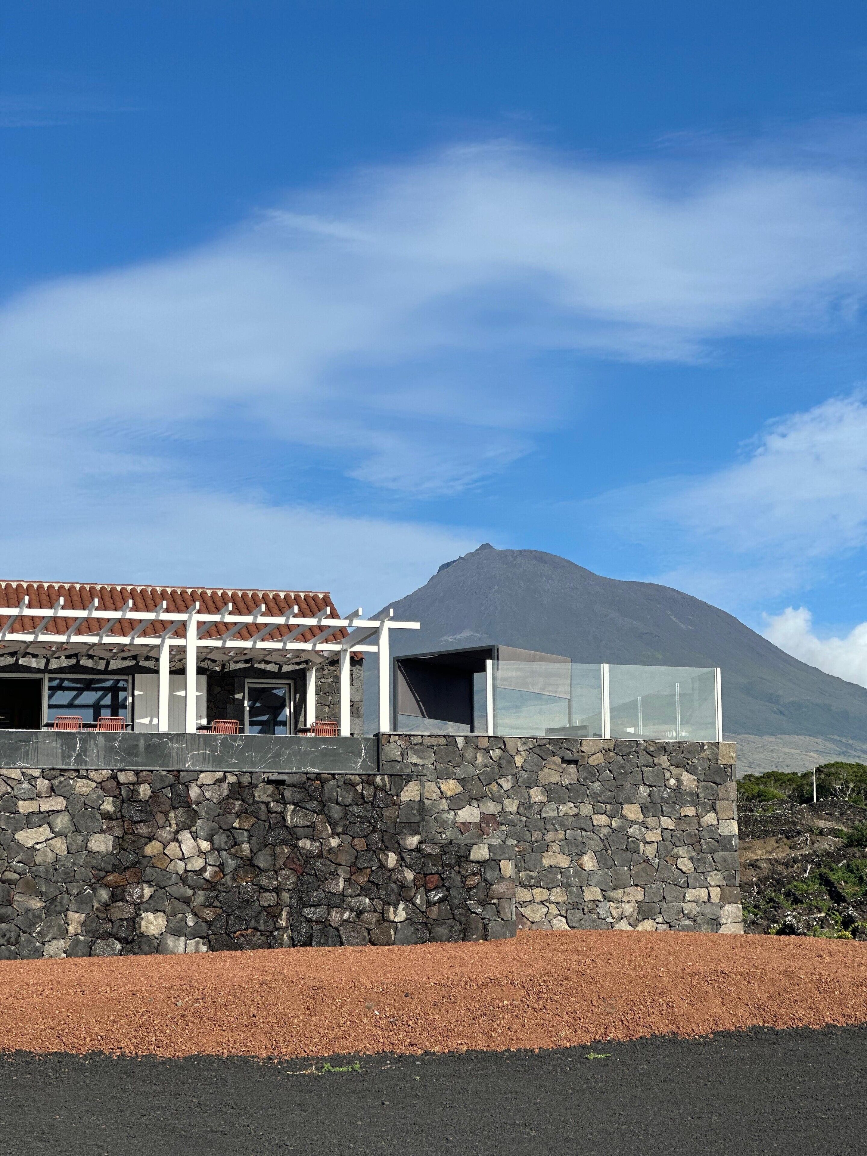 Un edificio moderno con fachada de piedra, un patio cubierto y vistas a una montaña.